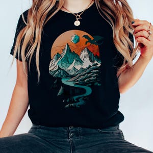 Close-up of a woman wearing the DnD adventure mountain shirt in navy — vintage fantasy landscape with D20 die visible, lifestyle shot showing print clarity and soft cotton fabric
