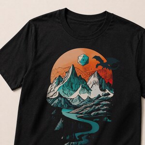 Front view of the DnD mountain adventure shirt in black — circular vintage fantasy landscape design with snowy peaks, pine trees, winding river, soaring eagle, and D20 die