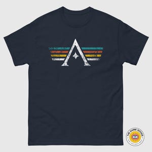 A minimalist t-shirt featuring the Arcs board game logo in a retro style. The design includes white geometric lines with a central star and vintage-colored stripes (teal, orange, red, yellow) on a dark background. Perfect for board gamers, sci-fi fans, and anyone who loves stylish and unique game night apparel.