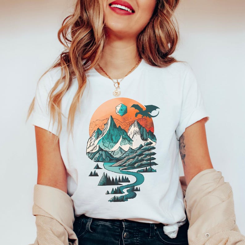 Woman wearing the DnD adventure mountain shirt in white — vintage fantasy landscape print with D20 and eagle, close lifestyle shot showing the circular design on a classic white tee