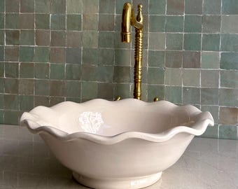 Lavabo de cerámica marroquí hecho a mano, con borde festoneado y diseño de flores blancas.