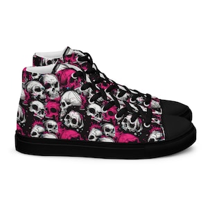 Könnte beinhalten: Schwarze High-Top-Canvas-Sneaker mit einem pinkfarbenen und weißen Totenkopf-Muster.
