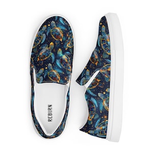 Könnte beinhalten: Ein Paar weiße Canvas-Slipper mit dunkelblauem Hintergrund und einem sich wiederholenden Muster aus bunten Meeresschildkröten. Die Schuhe haben das Wort "REBURN" auf der Innenseite des linken Schuhs aufgedruckt.