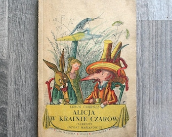 Puede incluir: Un libro antiguo titulado Alicja w Krainie Czarów de Lewis Carroll, con una colorida ilustración de una fiesta de té con un conejo, una persona y un personaje con un gran sombrero amarillo, todos sentados a una mesa con un mantel amarillo.