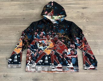 May include: Black hooded sweatshirt with a full-color print of a basketball game featuring two players in action. The print includes a crowd of spectators and the words "Lakers" and "24".