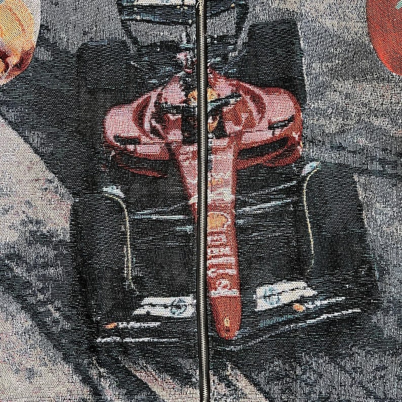 May include: A tapestry featuring a Formula 1 race car in red and black. The car's design is detailed, with the word "Shell" visible on the front. The background is a mix of gray and black, with a zipper running down the center.