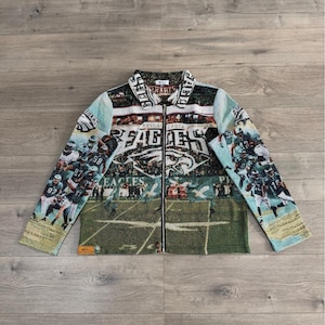 Peut inclure: Veste zippée avec un motif de tapisserie représentant le logo des Eagles de Philadelphie et des joueurs en action. La veste a un col et une fermeture éclair sur toute la longueur. La palette de couleurs comprend du vert, du blanc et du bleu.