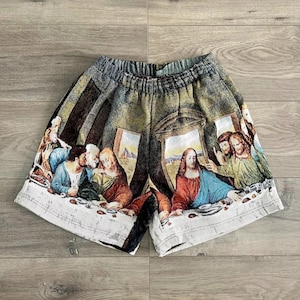 Op de afbeelding: Een wit en groen gepatroneerd short met een afbeelding van het Laatste Avondmaal. De short heeft een trekkoord in de taille en een ontspannen pasvorm.