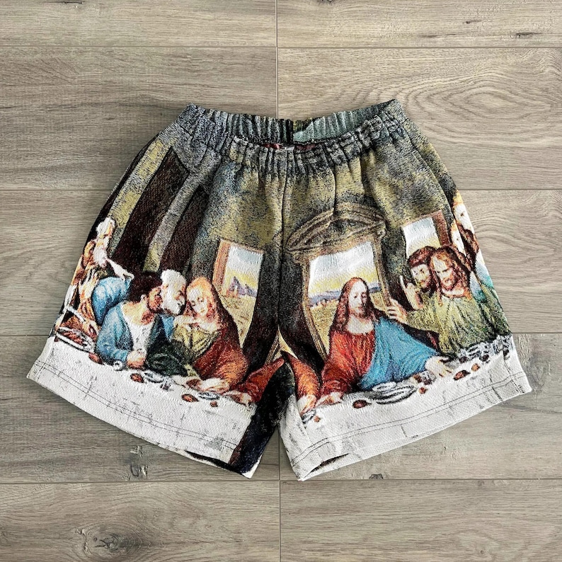 Op de afbeelding: Een wit en groen gepatroneerd short met een afbeelding van het Laatste Avondmaal. De short heeft een trekkoord in de taille en een ontspannen pasvorm.