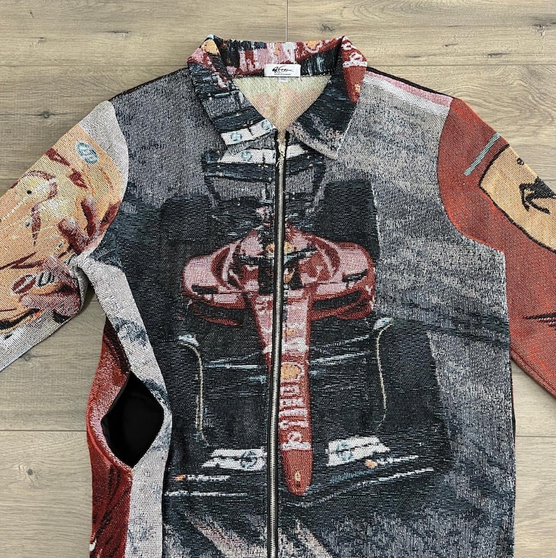 May include: A tapestry jacket with a full-length zipper and a collared neckline. The jacket features a Formula 1 race car design in shades of red, black, and gray. The sleeves and back panels have additional abstract patterns and colors.