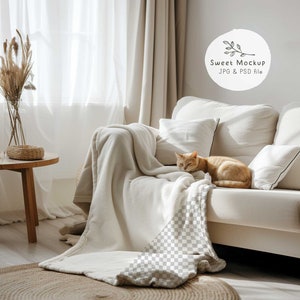 May include: A cozy living room scene featuring a cream-colored sofa with pillows, a soft blanket, and an orange cat resting on the cushions. A small wooden side table holds a vase of dried plants and a teacup. The text "Sweet Mockup JPG & PSD file" is visible.