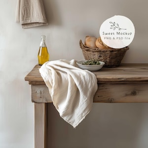 May include: A rustic wooden table with a white and gray checkered cloth draped over it. A bottle of olive oil and a bowl of herbs are on the table. A wicker basket filled with bread is in the background. The text "Sweet Mockup PNG & PSD file" is on a white circle with a branch and leaves.
