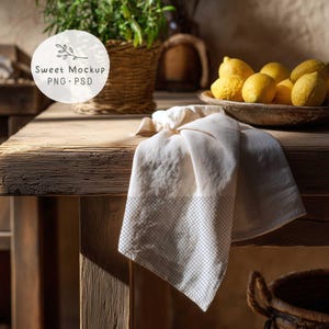 May include: A rustic wooden table with a folded white and gray patterned towel. A bowl of lemons sits on the table, and a woven basket with greenery is in the background. The image includes the text "Sweet Mockup PNG PSD".