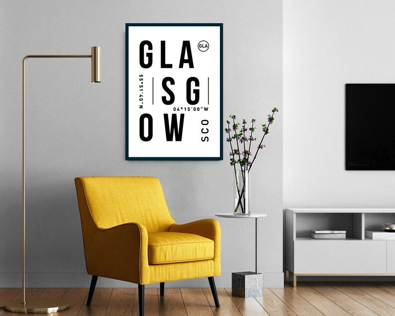 May include: A black and white poster with the word "GLASGOW" in large, bold letters. The poster also includes the coordinates "55&deg;51&prime;40&Prime;N 04&deg;15&prime;00&Prime;W" and the abbreviation "SCO" for Scotland. The poster is framed in a black frame and is hanging on a white wall.