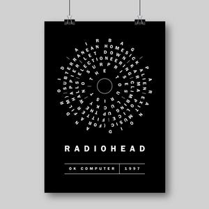 May include: Black poster featuring the band Radiohead's name in white capital letters. The poster includes the album title "OK Computer" and the year "1997". A circular design with white text surrounds a central circle. The poster is suspended by two black clips.