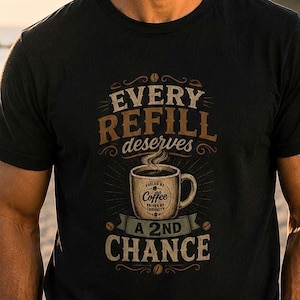 May include: A black short-sleeved t-shirt featuring a graphic of a coffee mug with steam and the text "EVERY REFILL deserves A 2ND CHANCE" printed in tan and white lettering, accented with small coffee bean illustrations and decorative lines.
