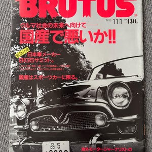 Peut inclure: Une couverture de magazine avec le titre "BRUTUS" en grandes lettres rouges. La couverture présente une image en noir et blanc d'une voiture classique. Du texte japonais est visible, dont l'année 1993 et le numéro de l'édition.
