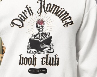 May include: White sweatshirt with a black and white graphic of a skeleton reading a book. The graphic says "Dark Romance Book Club Est. After Dark".