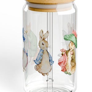 Puede incluir: Un tarro de vidrio transparente con tapa de bambú y una pajita de vidrio transparente. El tarro tiene un diseño de Peter Rabbit y sus amigos.