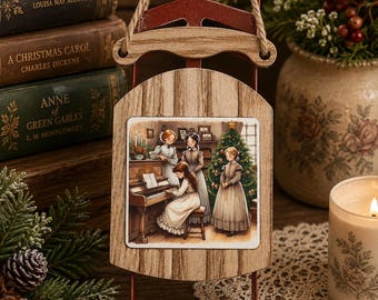 May include: A decorative wooden sled ornament featuring a printed illustration of four figures in period clothing gathered around a piano and a Christmas tree. The sled has a natural wood finish, a red metal frame, and a jute rope hanger at the top.