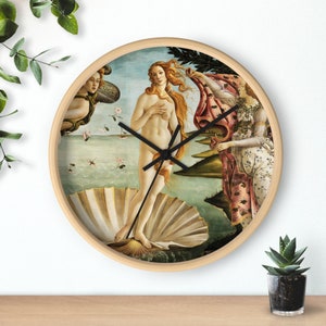 May include: A round wooden clock with a white background featuring a painting of the Birth of Venus by Sandro Botticelli. The clock has black hands and a black rim.