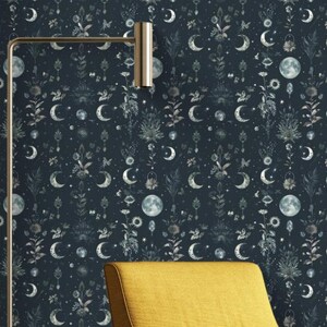 May include: A mustard yellow armchair with black legs sits in front of a dark blue wall with a repeating pattern of white moons, stars, and floral designs.