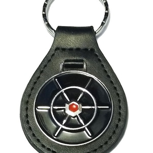 May include: Black leather keyring with a silver metal wheel design and a red centre. The keyring has a silver metal ring.