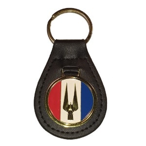 May include: Black leather keychain with a gold-colored circular emblem featuring a white bird with red and blue accents.