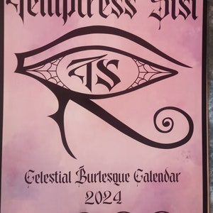 May include: A pink and black calendar with the title "Temptress Sisi Celestial Burlesque Calendar 2024". The calendar features an eye with a web design and the letters "TS" in the center.