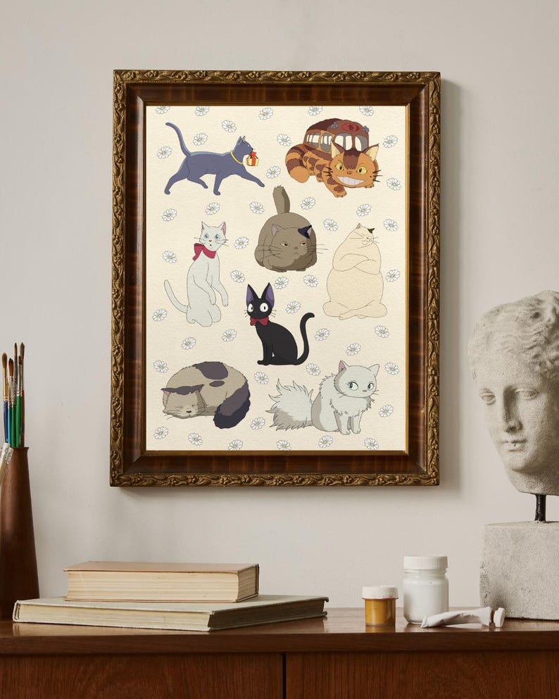 May include: A framed print featuring various cartoon cat illustrations. The cats are in different poses and colors, set against a cream background with small floral patterns. The frame is a dark, ornate wood. The print is displayed on a wooden surface.