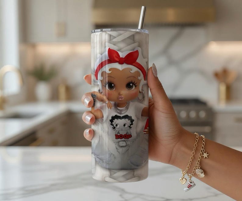 May include: A stainless steel tumbler with a cartoon character design, featuring a red bow and a white t-shirt with a graphic. The tumbler has a silver straw and a white and grey background.