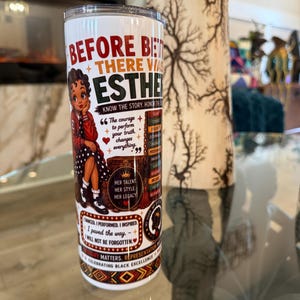 May include: A white cylindrical tumbler featuring a graphic illustration of a person, the text BEFORE BETTY THERE WAS ESTHER, and various inspirational quotes. The design includes red, black, and gold accents, with patterns celebrating Black excellence.