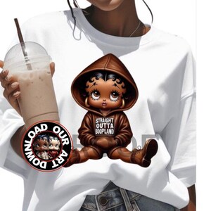 May include: White sweatshirt featuring a cartoon image of a Betty Boop-like character in a brown hoodie and boots. The hoodie has the text "STRAIGHT OUTTA BOOPLAND". A circular logo with the words "DOWNLOAD OUR ART" is also visible.