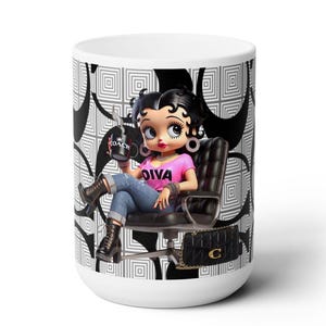 May include: White ceramic mug with a black and white geometric pattern. The mug features a cartoon image of a female character with black hair, wearing a pink shirt with the word "Diva" on it, blue jeans, and black boots. She is sitting in a black chair and holding a coffee cup with the word "Coach" on it. The mug also features a black purse with a gold "C" on it.