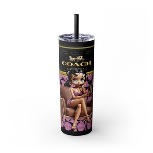 May include: A black and pink stainless steel tumbler with a cartoon image of a woman sitting on a chair. The tumbler has the word "COACH" printed on it.