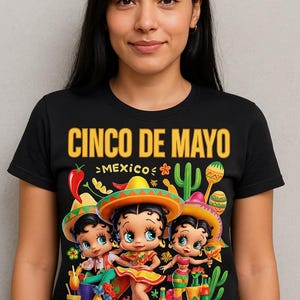May include: Black t-shirt with a colorful Cinco de Mayo graphic. The design features three cartoon characters wearing sombreros, surrounded by cacti, maracas, and the text "Cinco de Mayo" and "Mexico".