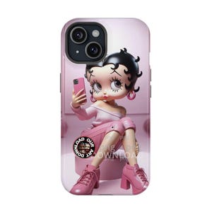 Puede incluir: Funda de teléfono rosa con un diseño de dibujos animados de Betty Boop haciéndose un selfie. La funda tiene un acabado brillante y cubre la parte trasera y los laterales. El personaje viste de rosa y sostiene un teléfono rosa.