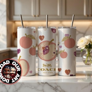 May include: Three white insulated tumblers with peach and heart designs. Each tumbler has a silver straw and a peach graphic. One tumbler features a Coach New York logo. The tumblers are on a marble countertop.