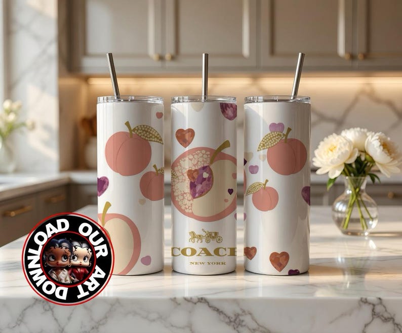 May include: Three white insulated tumblers with peach and heart designs. Each tumbler has a silver straw and a peach graphic. One tumbler features a Coach New York logo. The tumblers are on a marble countertop.