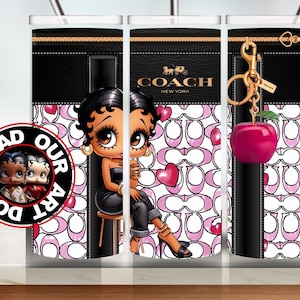May include: A tumbler featuring a cartoon character design, a black leather-like top with a gold zipper, and a pink and white pattern. The tumbler has a Coach logo and a pink apple keychain.