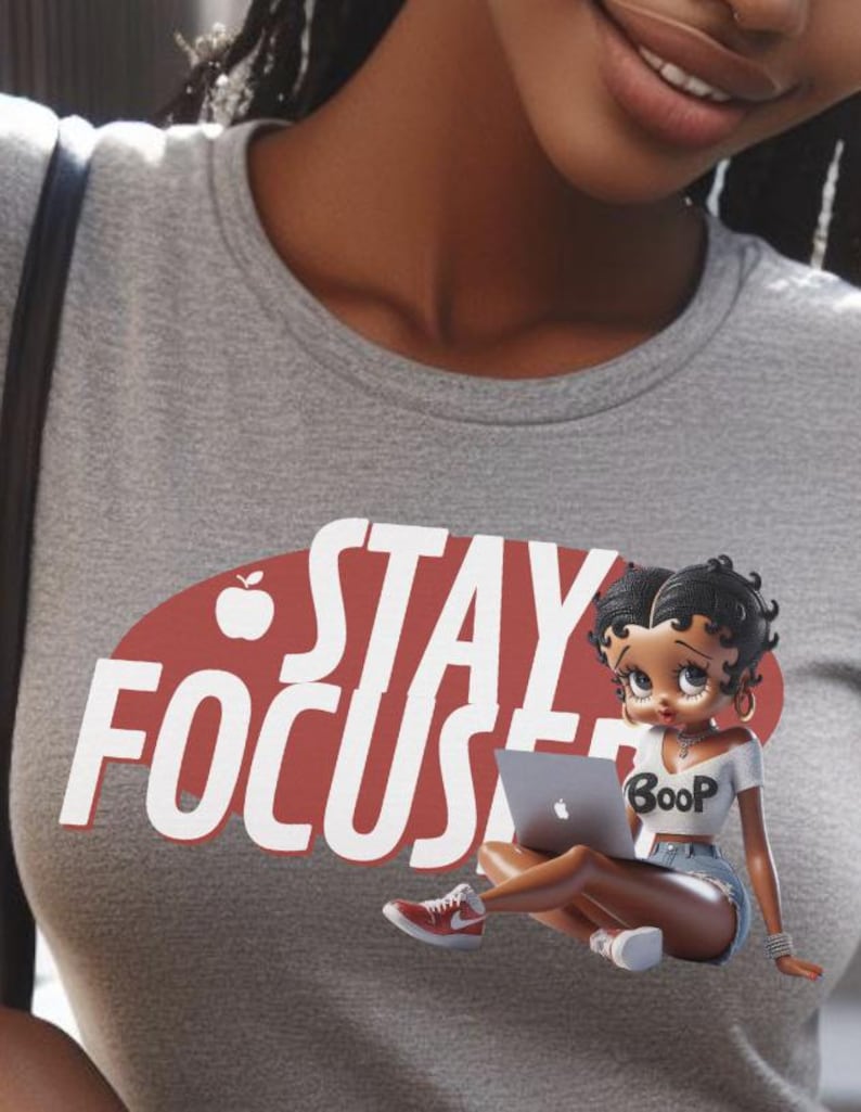 May include: Gray t-shirt with the words "STAY FOCUS" in white letters over a red oval. A cartoon figure of a woman wearing a white crop top with "Boop" on it, denim shorts, and red sneakers is holding a laptop.