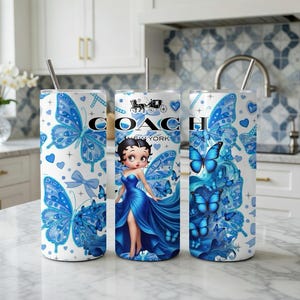 Może przedstawiać: Trzy białe kubki ze stali nierdzewnej z niebieskimi wzorami motyli i serc. Jeden kubek ma grafikę Betty Boop i logo Coach New York. Każdy kubek ma srebrną słomkę i pokrywkę.