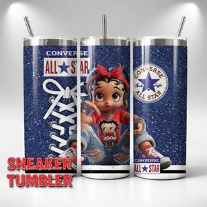 May include: A stainless steel tumbler with a blue glitter background featuring a Betty Boop cartoon character wearing a red shirt and ripped jeans. The tumbler has a Converse All Star logo and a sneaker lace design. The words "Sneaker Tumbler" are at the bottom.
