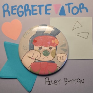 May include: A round Pilby button featuring a cartoon character with a sad expression, a red bow, and a green nose. The button is surrounded by a blue star, a pink heart, and the text "REGRETETOR" and "Pilby Button".
