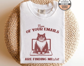 May include: White t-shirt with a red graphic of a cat wearing glasses and sitting in front of a laptop. The text reads "None of your emails are finding me well."