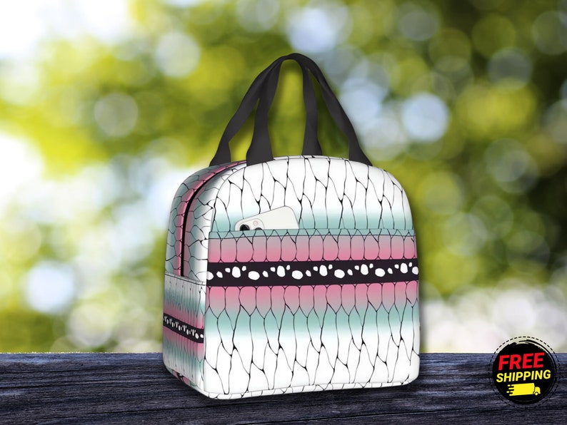 K&ouml;nnte beinhalten: Eine wei&szlig;e Lunch-Tasche mit einem geometrischen Muster in Schwarz und Rosa. Die Tasche hat einen schwarzen Griff und eine kleine Tasche auf der Vorderseite.