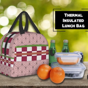 K&ouml;nnte beinhalten: Rosa-rote karierte Lunch-Tasche mit geometrischem Muster. Die Tasche hat einen schwarzen Griff und einen Rei&szlig;verschluss. Der Text "THERMAL INSULATED LUNCH BAG" ist in einem wei&szlig;en Kasten dargestellt. Die Tasche liegt auf einem Holztisch mit zwei Orangen, zwei Glasbeh&auml;ltern und einer Dose.