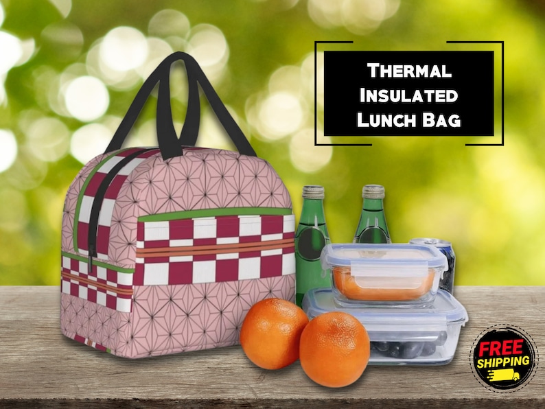K&ouml;nnte beinhalten: Rosa-rote karierte Lunch-Tasche mit geometrischem Muster. Die Tasche hat einen schwarzen Griff und einen Rei&szlig;verschluss. Der Text "THERMAL INSULATED LUNCH BAG" ist in einem wei&szlig;en Kasten dargestellt. Die Tasche liegt auf einem Holztisch mit zwei Orangen, zwei Glasbeh&auml;ltern und einer Dose.