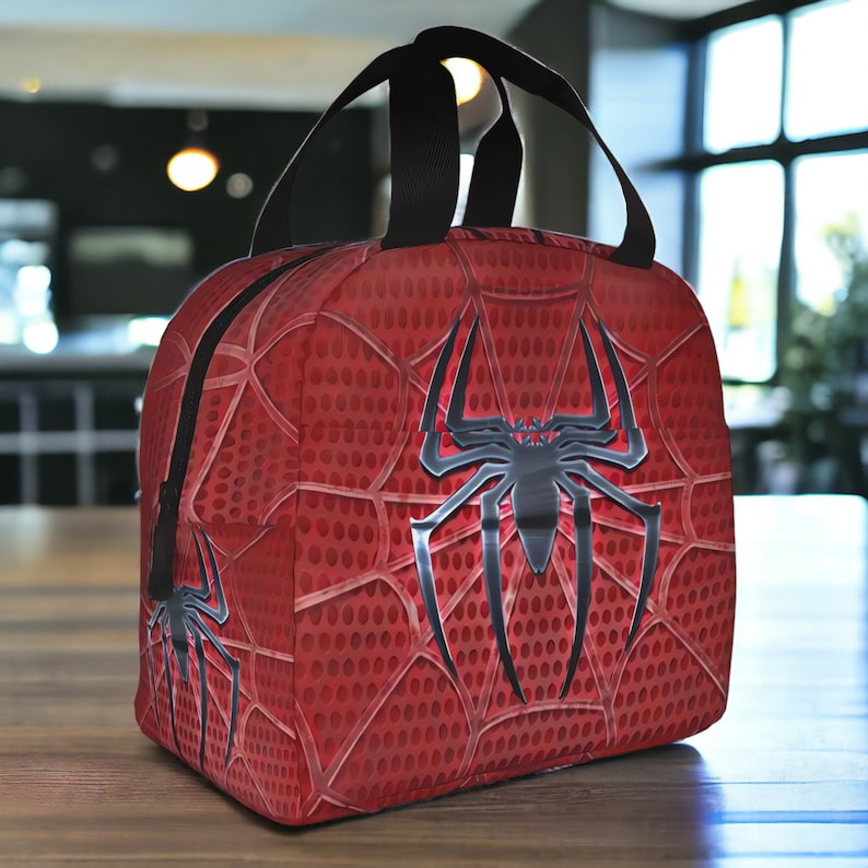 May include: Red lunch bag with a black spider web design and a black spider in the centre.