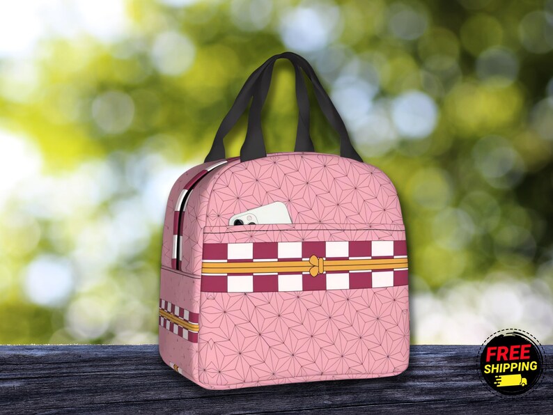 K&ouml;nnte beinhalten: Rosa Lunch Bag mit kariertem Muster und Blumendesign. Die Tasche hat einen Rei&szlig;verschluss und einen oberen Griff.